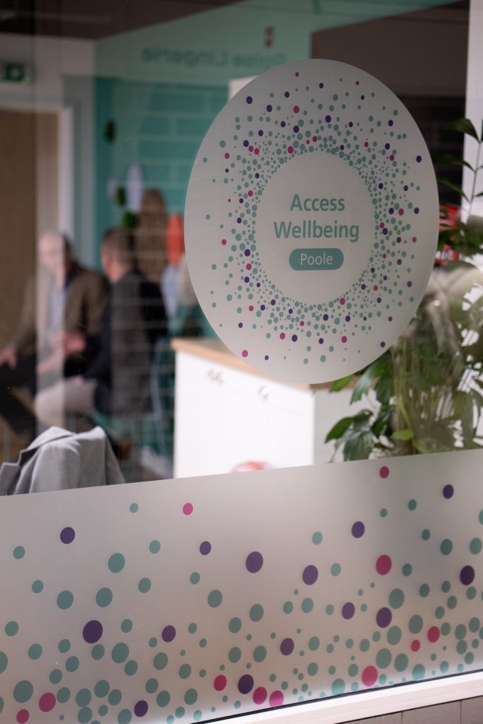 The exterior of the Access Wellbeing hub in Poole, showing people chatting inside