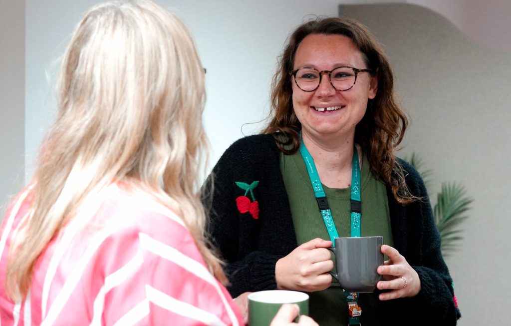 Two members of Access Wellbeing staff chat over coffee