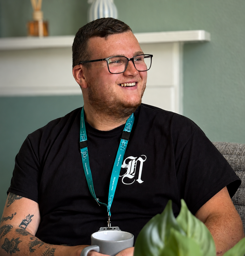 A wellbeing coordinator holds a cup of tea whilst chatting to someone else